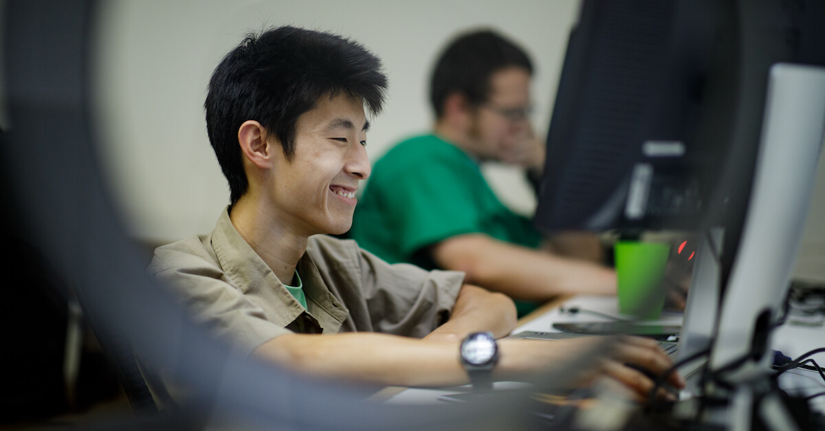 An employee sits at his computer and smiles