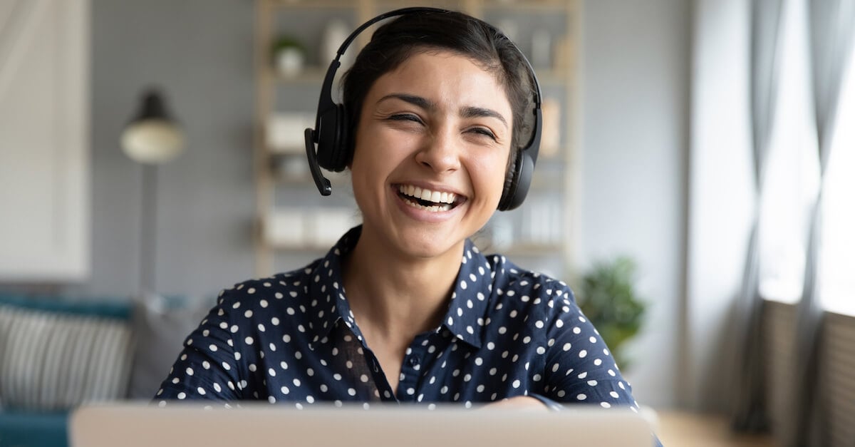 An employee at her desk wearing headphones and smiling
